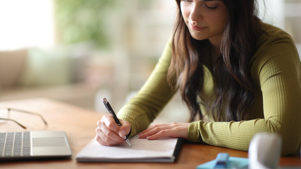 Persona tomando notas a mano en un cuaderno