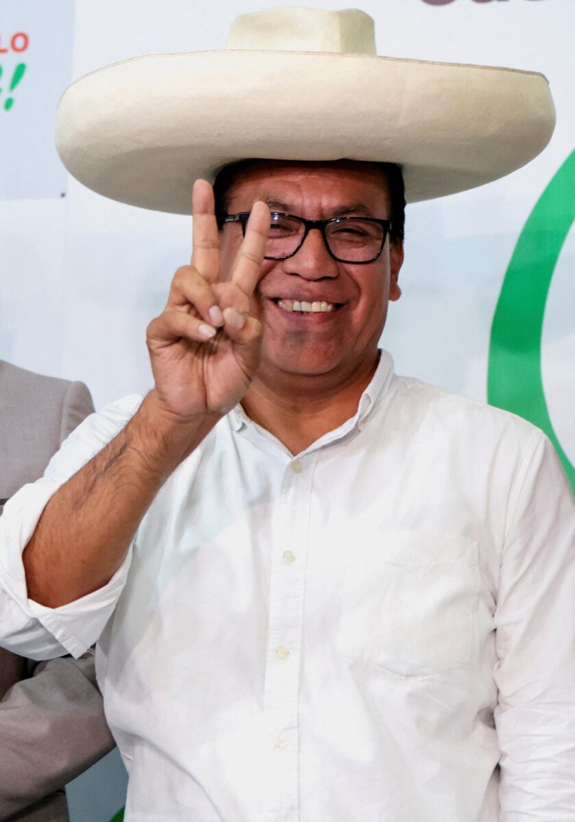 Roberto Sánchez sonríe y hace el signo de la paz con las manos durante un evento electoral en Perú