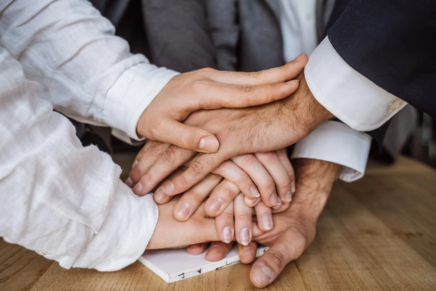 Manos de diferentes generaciones unidas sobre una mesa, simbolizando la conexión familiar