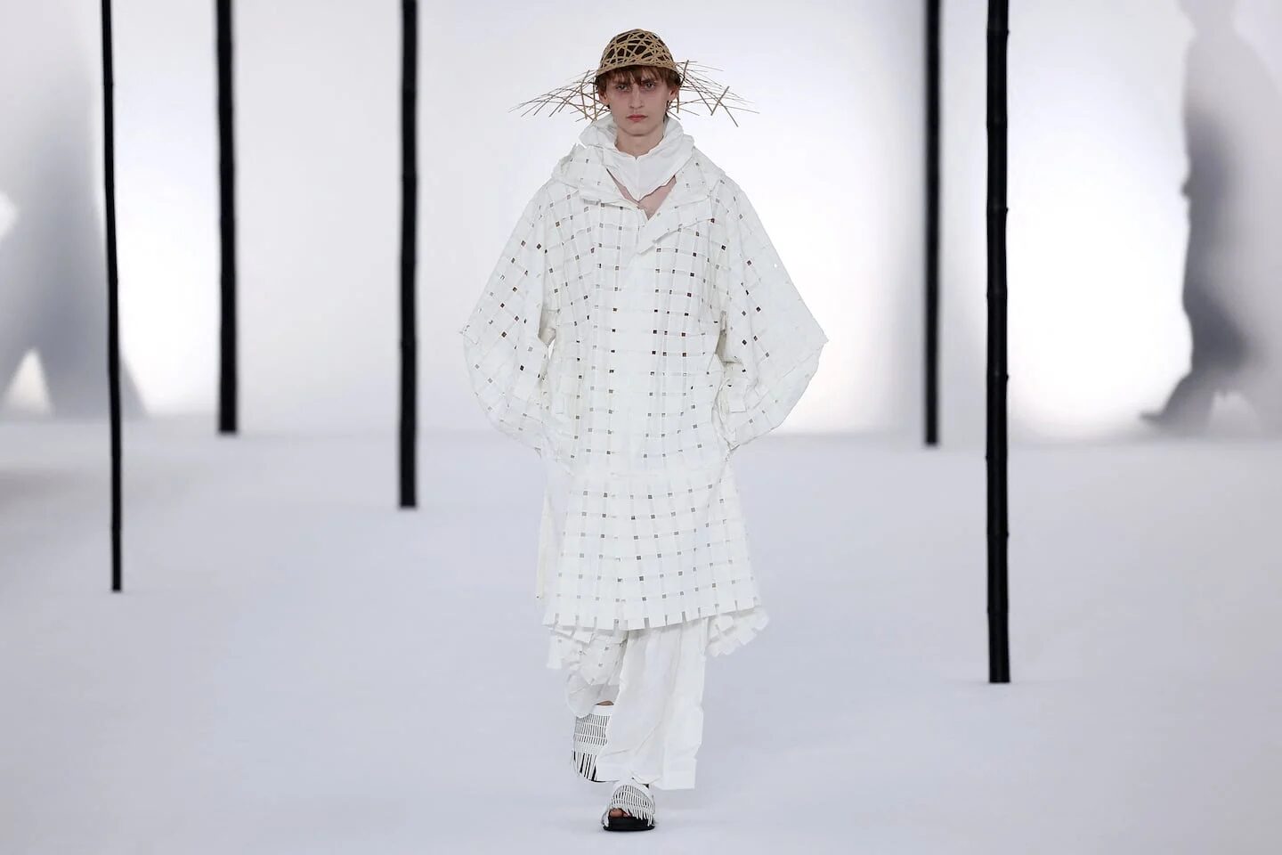 Modelo vestido con atuendo blanco y sombrero de paja en la Semana de la Moda Masculina de París