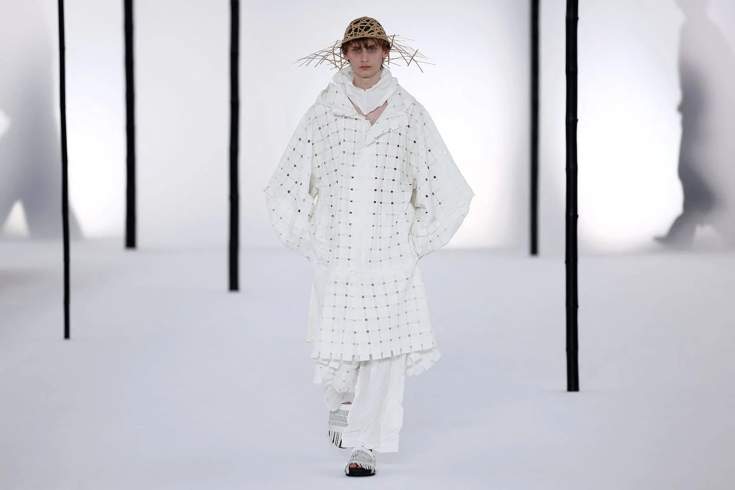 Modelo vestido con atuendo blanco y sombrero de paja en la Semana de la Moda Masculina de París
