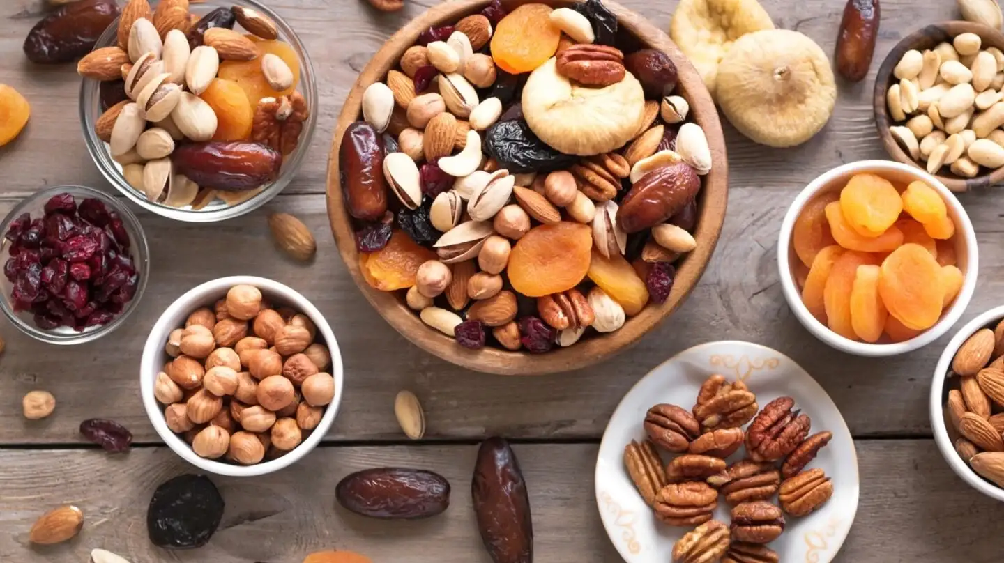 Mezcla de frutos secos y deshidratados en recipientes sobre una mesa de madera