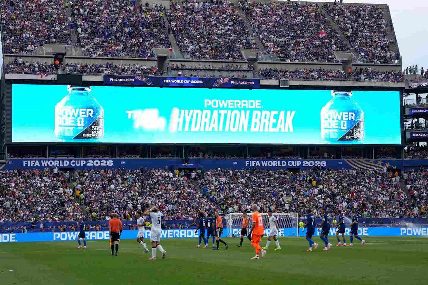 Jugadores en el Estadio MetLife durante un partido del Mundial 2026 con un anuncio sobre hidratación