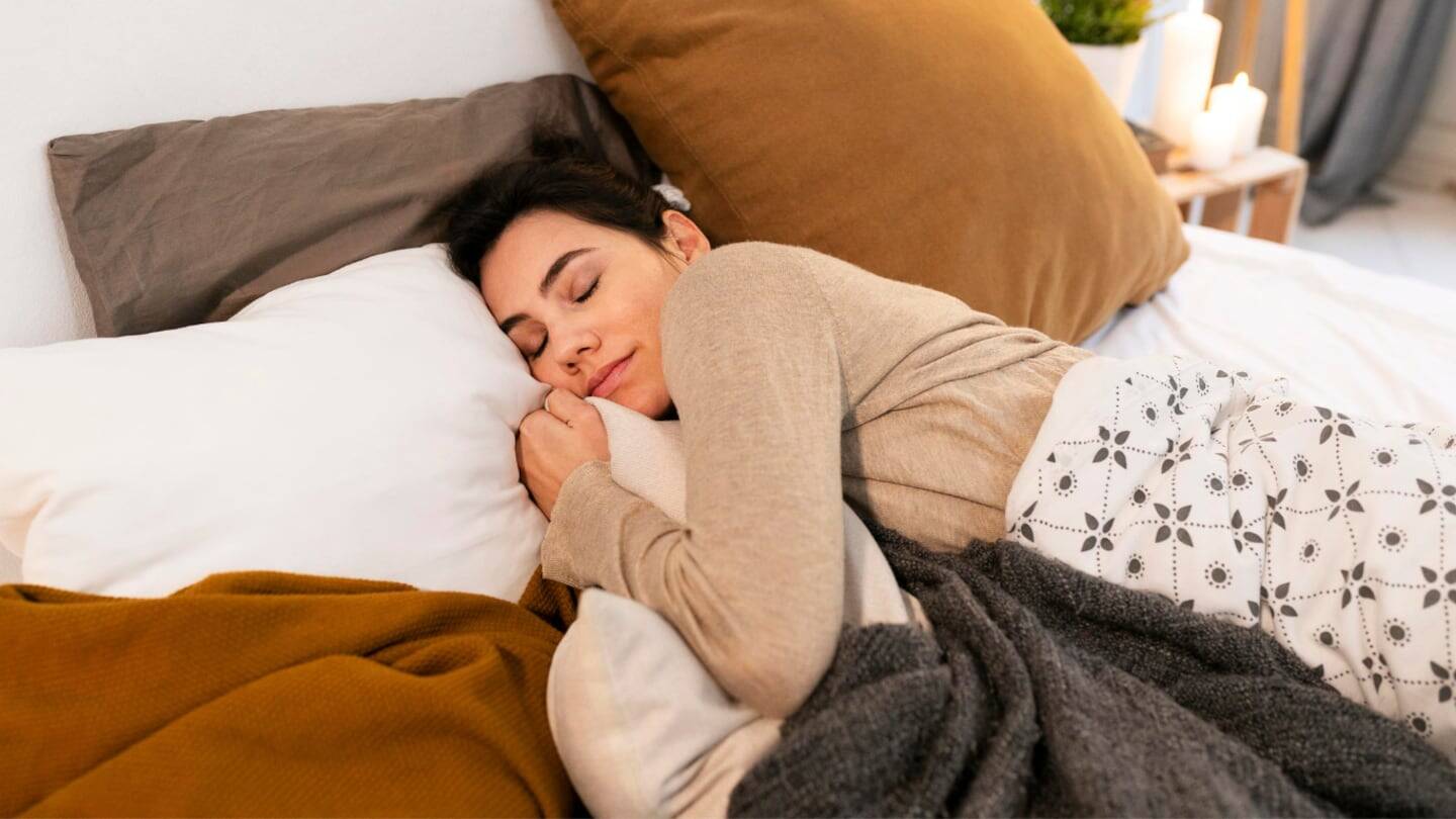 Mujer durmiendo en una cama con almohadas y mantas