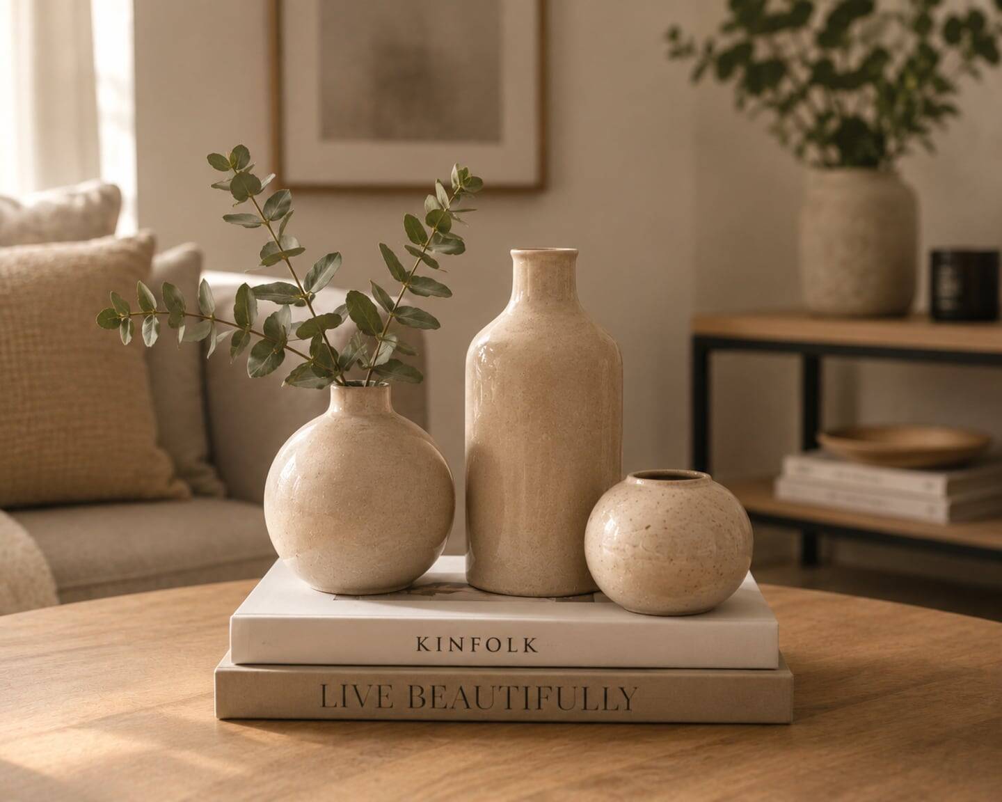 Tres jarrones de cerámica en una mesa de madera con libros decorativos