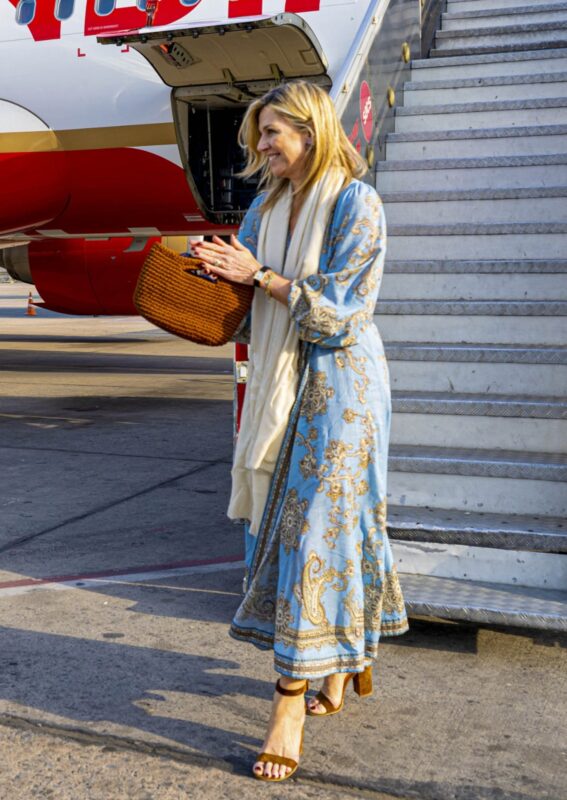 La reina Máxima de Holanda descendiendo de un avión en India con un vestido celeste y un bolso artesanal
