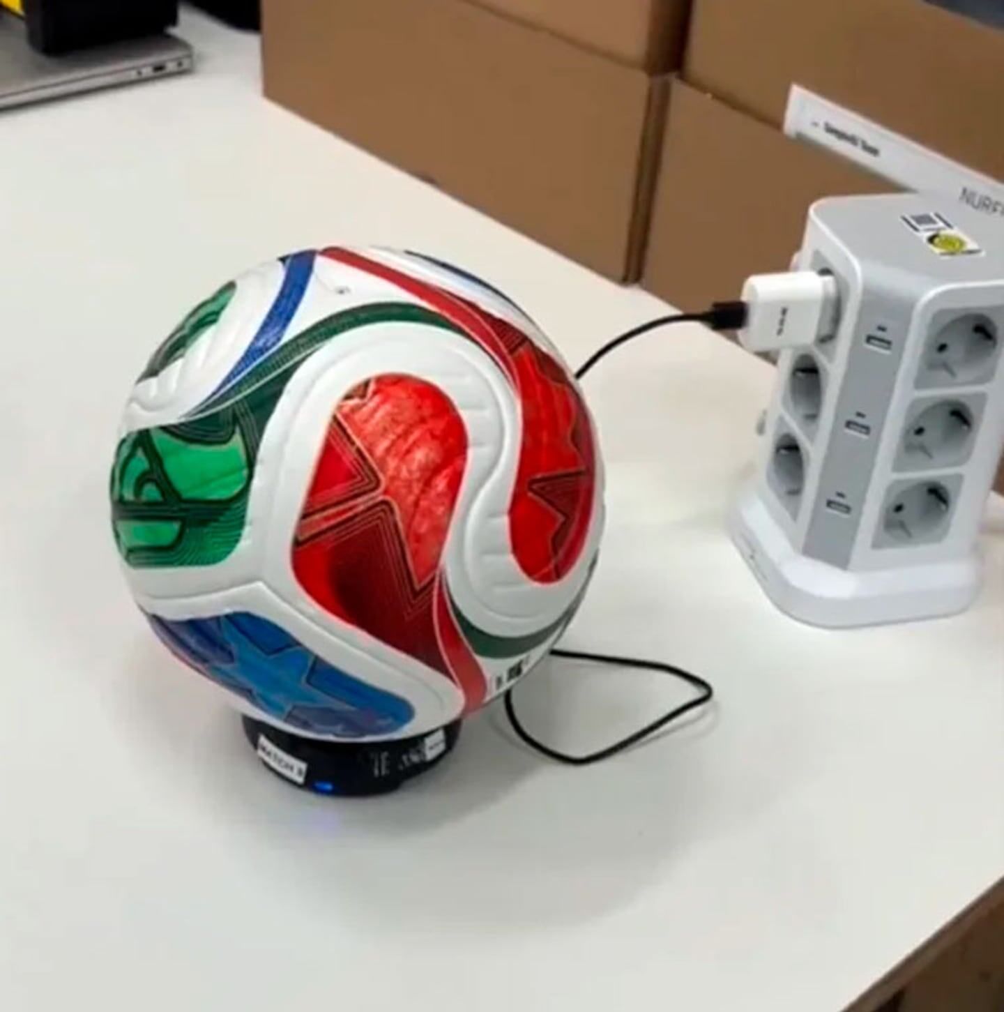 Balón de fútbol conectado a un cargador en un entorno tecnológico