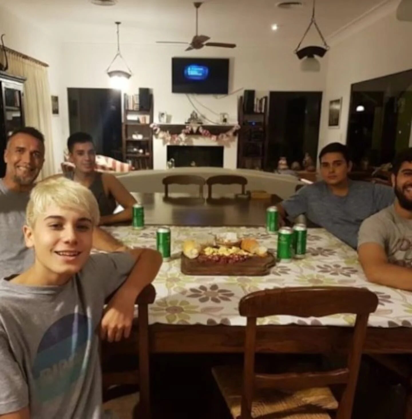 Grupo de amigos y familiares reunidos alrededor de una mesa de madera en un ambiente acogedor