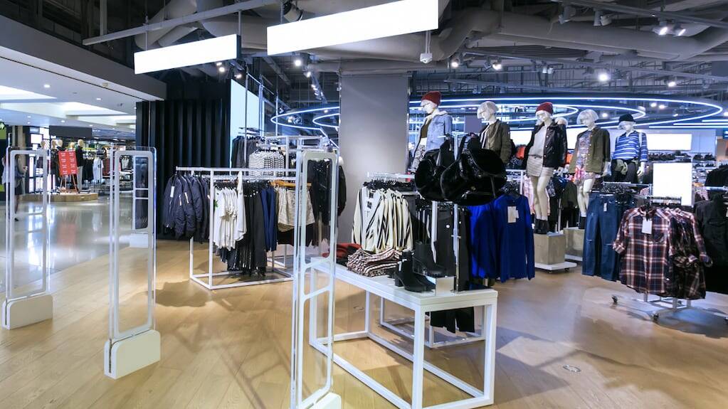 Interior de un supermercado con estantes vacíos y ropa exhibida