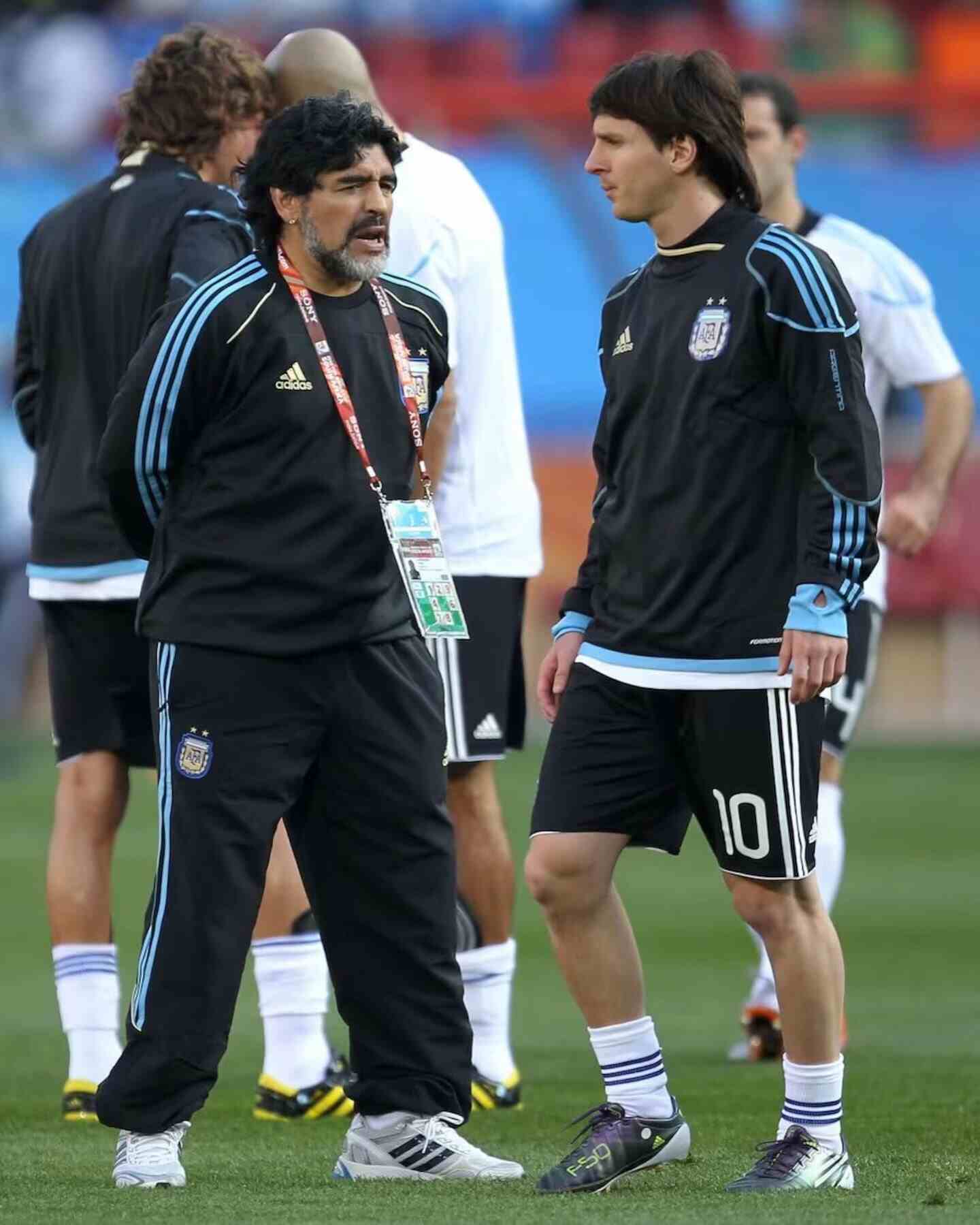 Lionel Messi y Diego Maradona conversan en el campo de juego durante un evento deportivo