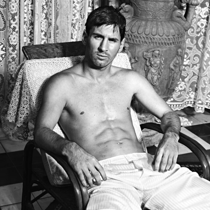 Lionel Messi posando sin camiseta en una silla, luciendo un look relajado