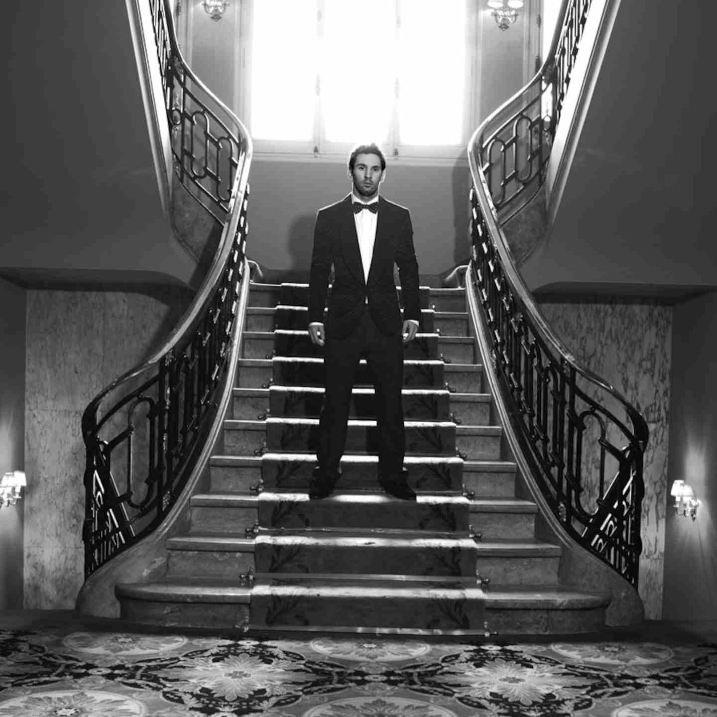 Lionel Messi posando en un elegante traje en una escalera de un edificio lujoso