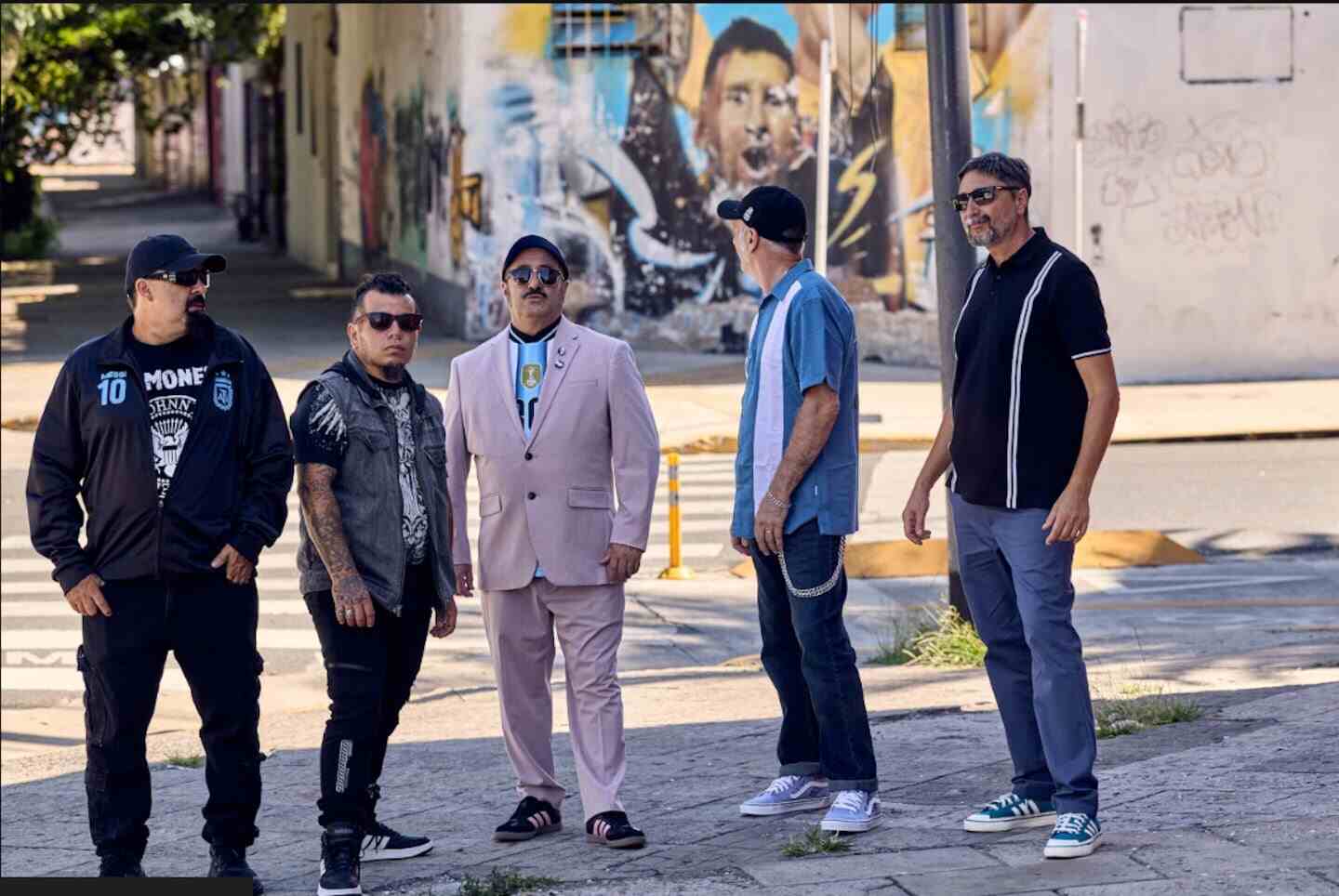 Los Calzones, banda argentina, posando frente a un mural en un entorno urbano