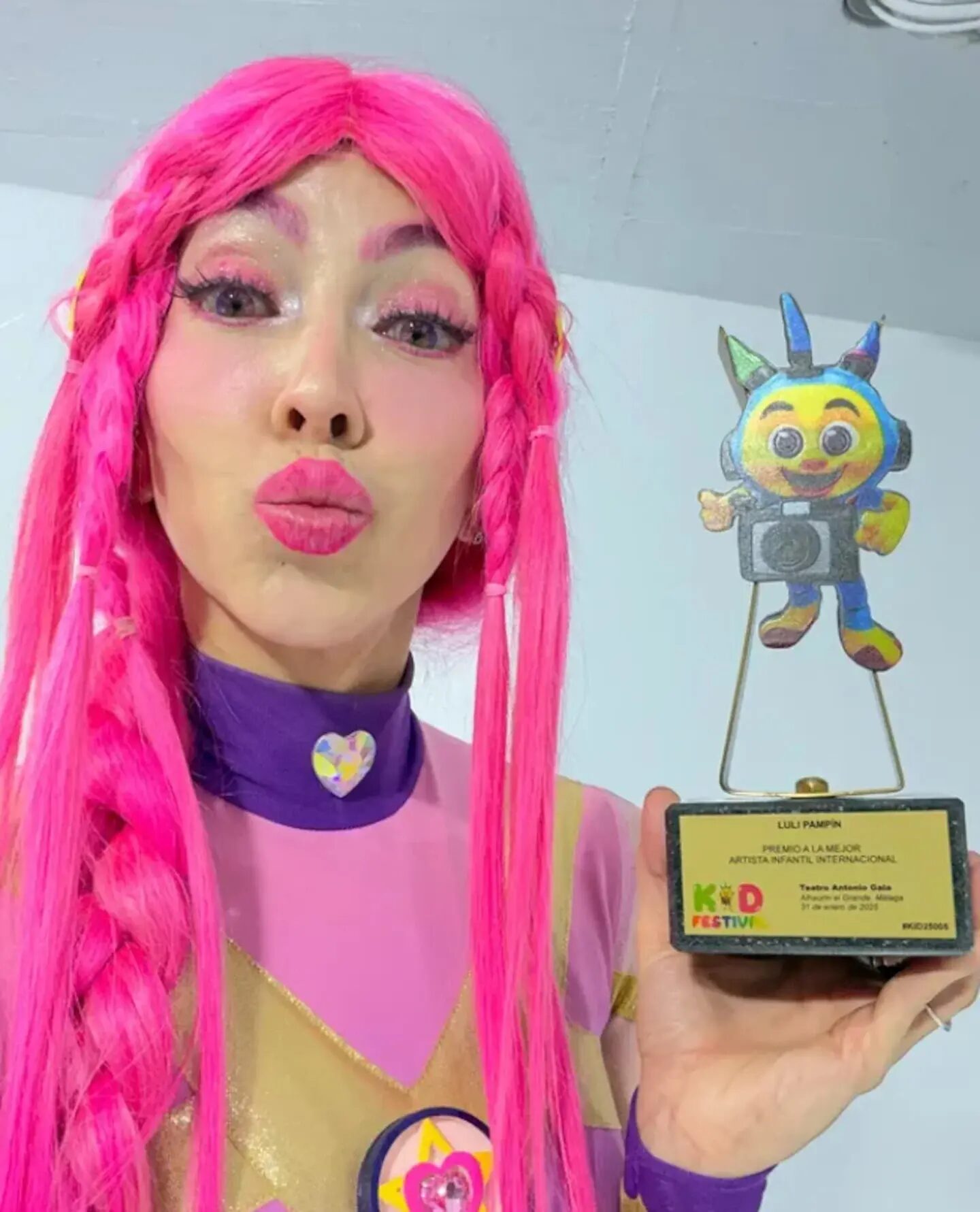 Luli Pampín sosteniendo un premio en un evento infantil con un fondo neutro