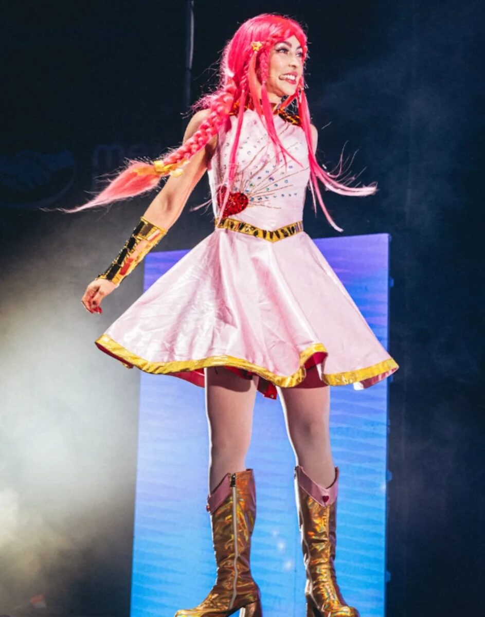 Luli Pampín en un espectáculo musical con vestido rosa y cabello rosa brillante