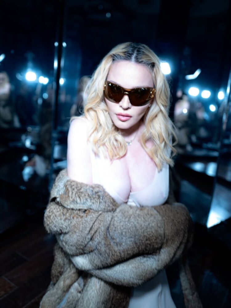 Madonna posando con gafas de sol y un abrigo de piel en un entorno reflejante