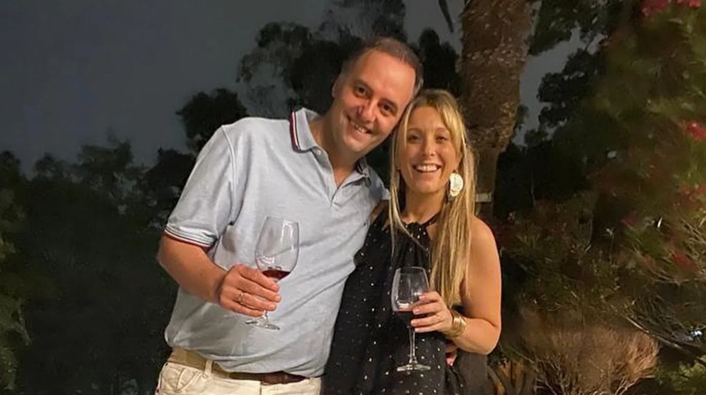 Manuel Adorni y una mujer sosteniendo copas de vino en un ambiente al aire libre