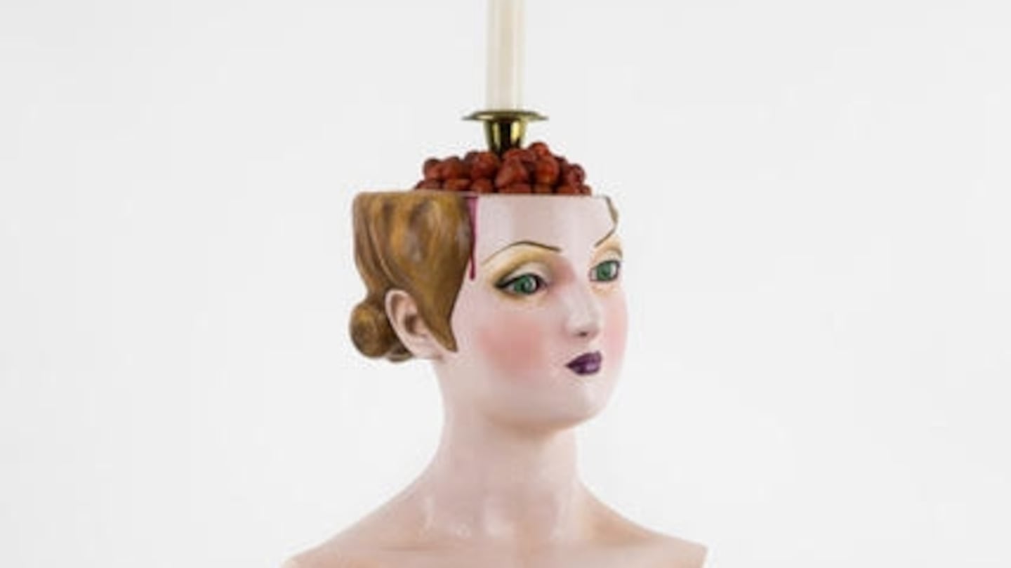 Escultura de busto femenino con una vela y cerezas en la cabeza