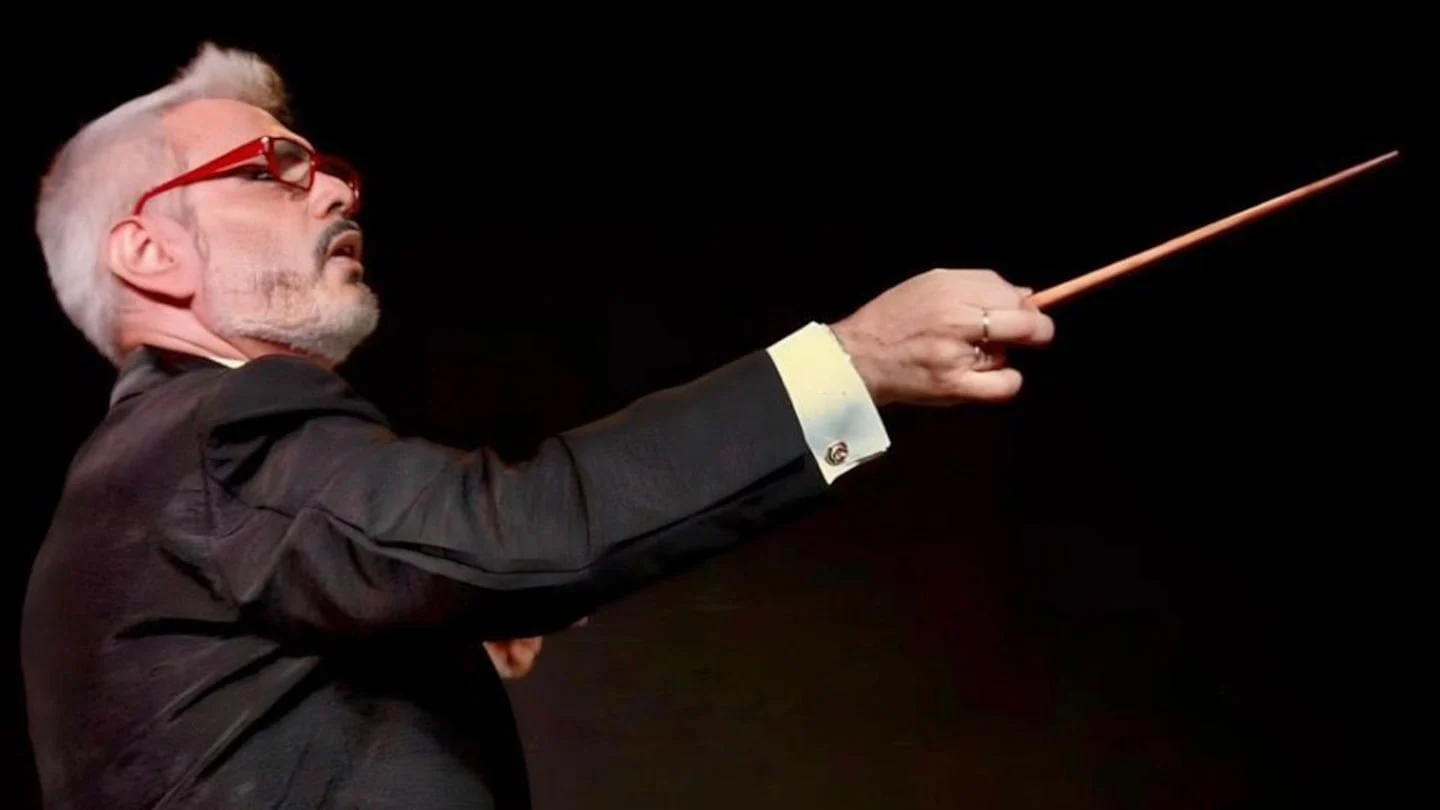 Director de orquesta señalando con batuta durante una actuación