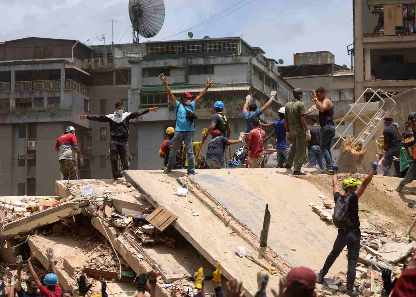 Grupo de personas levantando los brazos sobre escombros tras un terremoto en Venezuela