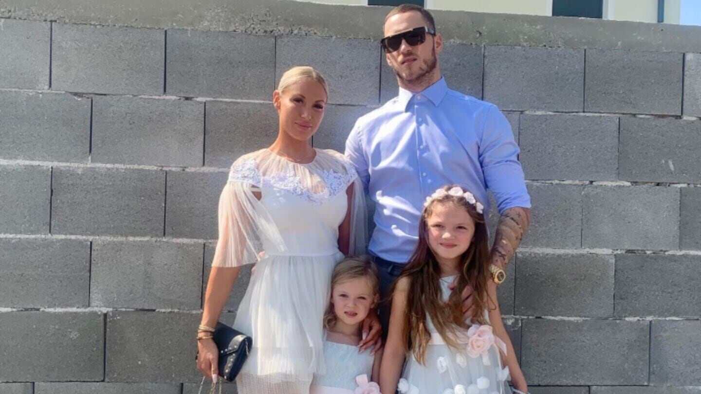 Marko Arnautovic posando con su familia frente a una pared de bloques de cemento