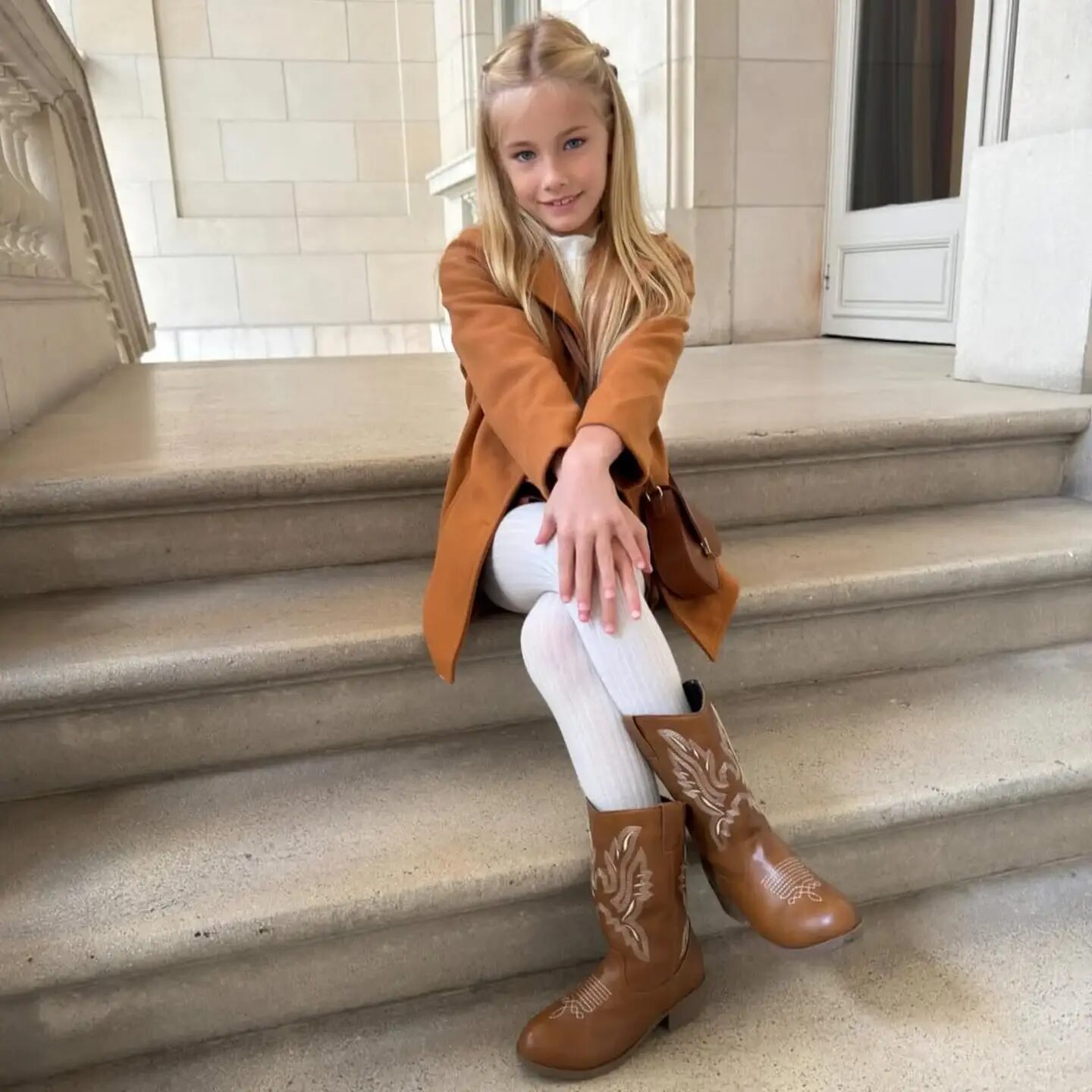 Matilda Salazar posando con un abrigo marrón y botas en una escalera