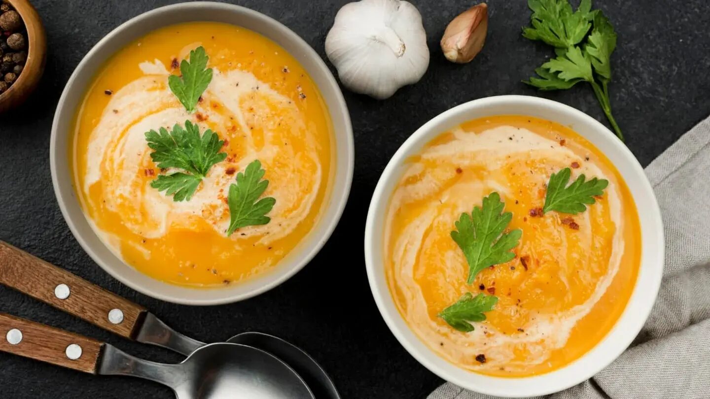 Crema de zapallo servida en dos tazones con perejil y ajo