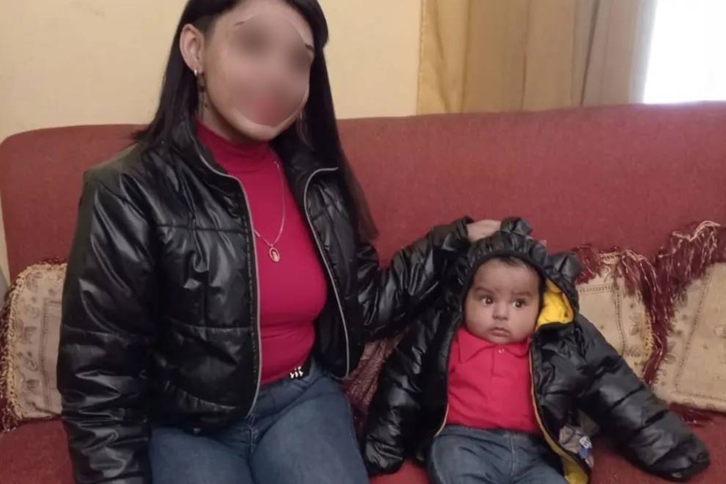 Madre y niño de dos años en un sofá, ambos con ropa de abrigo