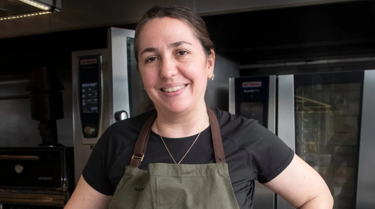 Narda Lepes sonríe mientras viste un delantal en una cocina profesional