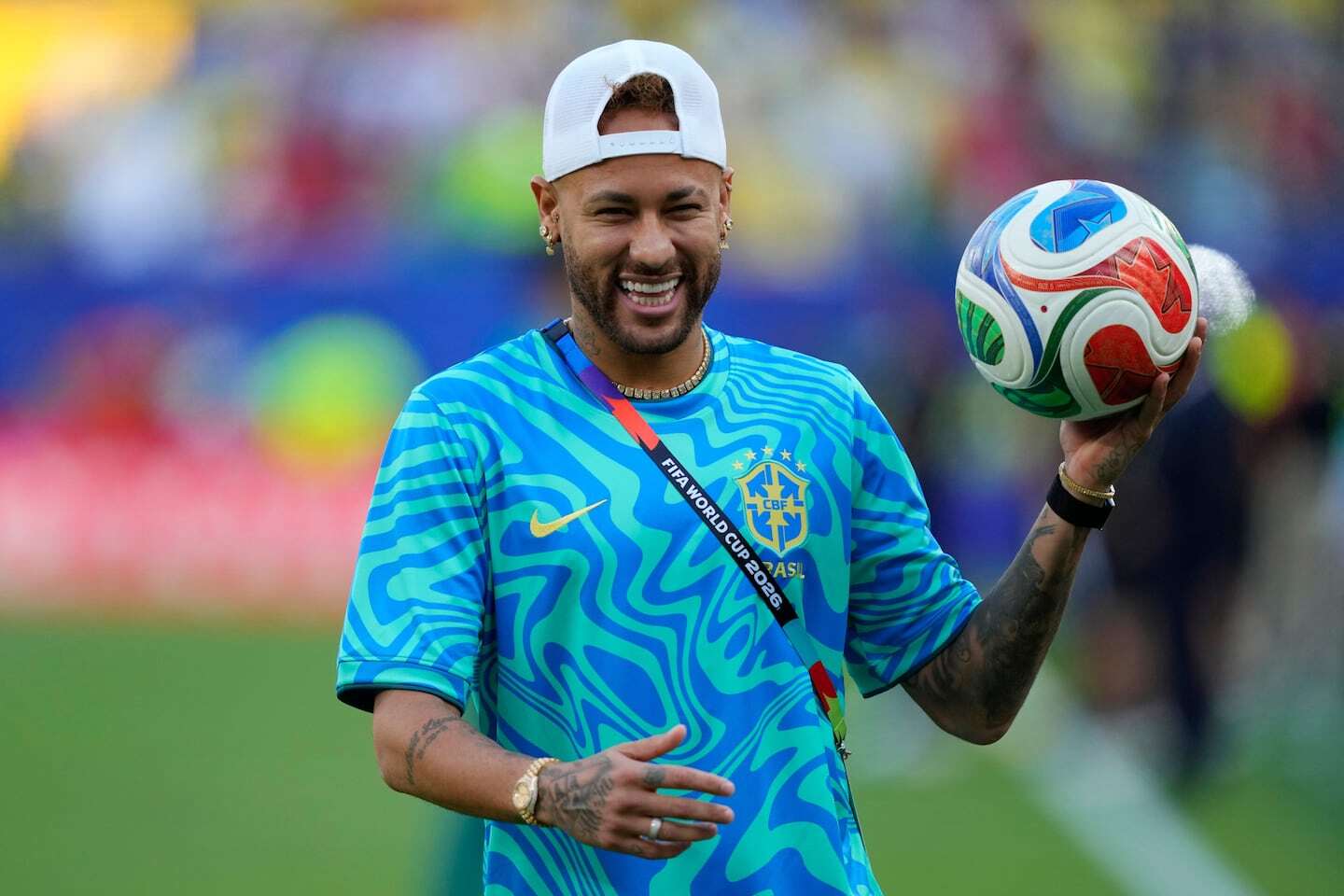 Neymar sonriente sosteniendo un balón de fútbol con la camiseta de Brasil