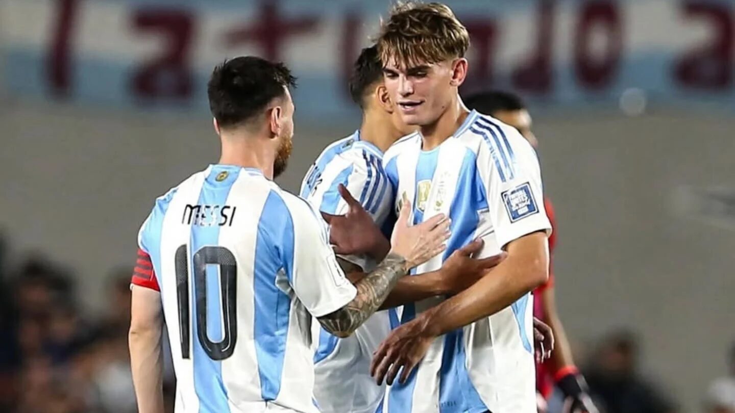 Nico Paz recibe instrucciones de Lionel Messi durante un partido de la selección argentina