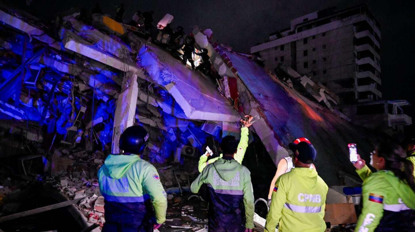 Edificio colapsado en Venezuela tras terremotos, con rescatistas trabajando en la escena