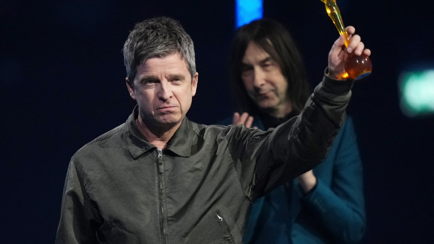 Noel Gallagher levantando un trofeo en un evento relacionado con el Mundial 2026