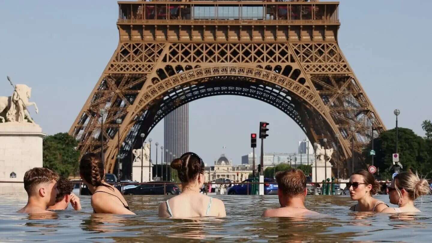 Personas en el agua frente a la Torre Eiffel durante una ola de calor en Europa