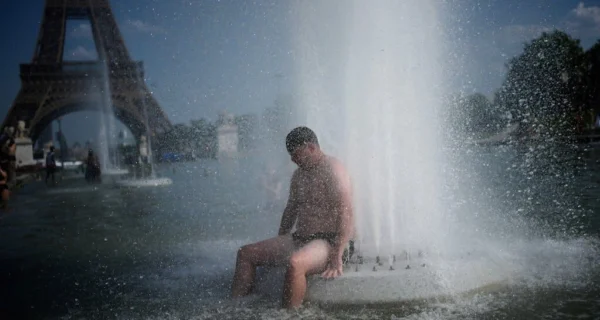 Ola de calor en Francia con personas refrescándose en una fuente cerca de la Torre Eiffel