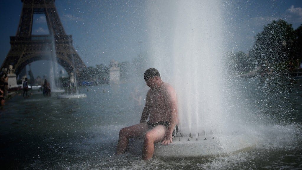 Ola de calor en Francia con personas refrescándose en una fuente cerca de la Torre Eiffel