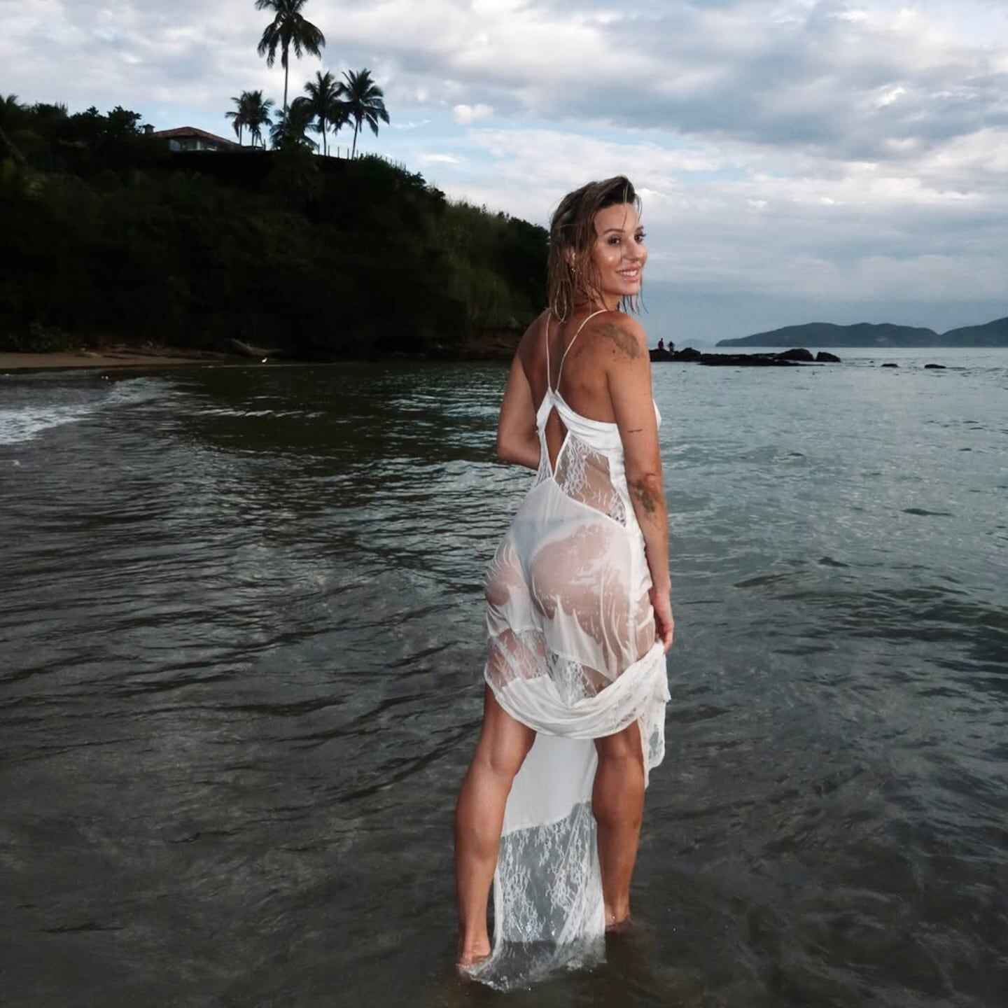 Mujer de espaldas en la playa con vestido lencero blanco