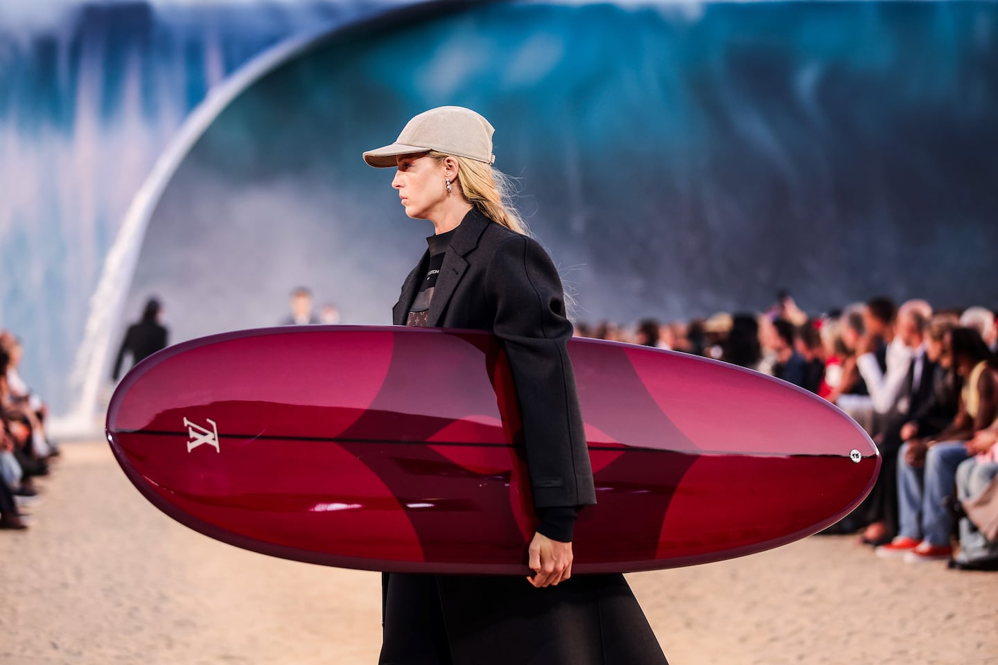Modelo con tabla de surf de Louis Vuitton en desfile de Pharrell Williams en París