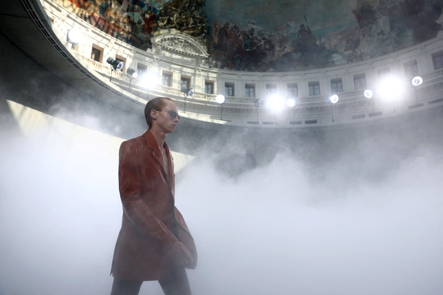 Modelo caminando en un desfile de Pharrell Williams para Louis Vuitton en París, rodeado de niebla