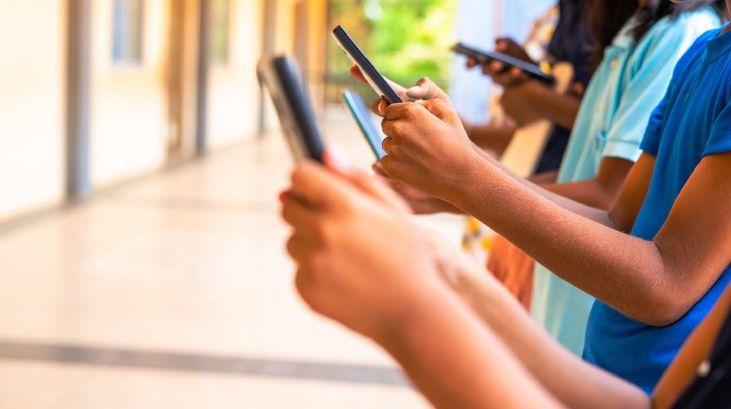 Grupo de jóvenes usando teléfonos móviles en un entorno escolar