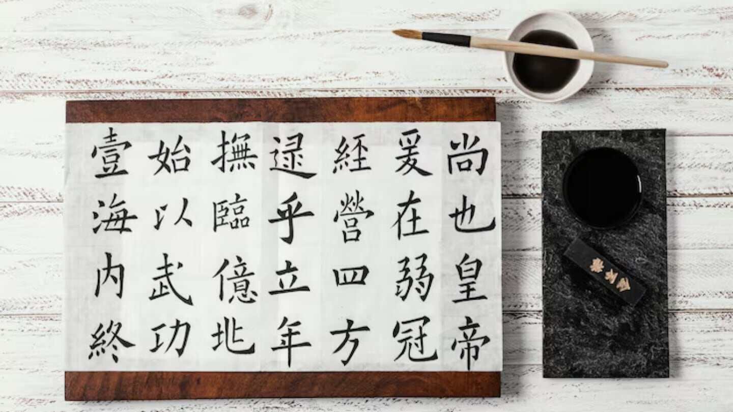 Papel con proverbio chino escrito en caracteres tradicionales sobre una mesa de madera