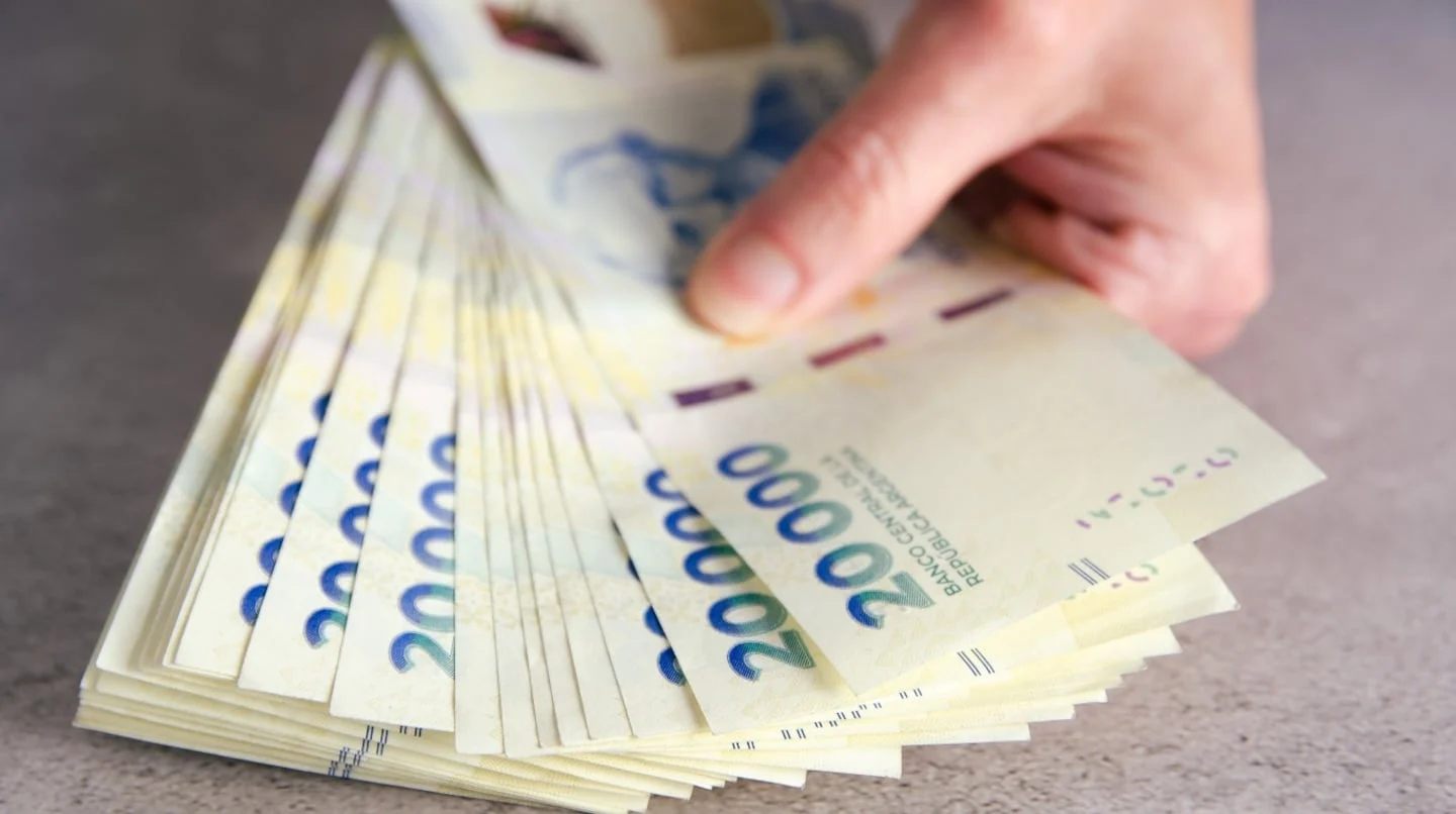 Billetes de 20.000 pesos argentinos apilados sobre una superficie plana