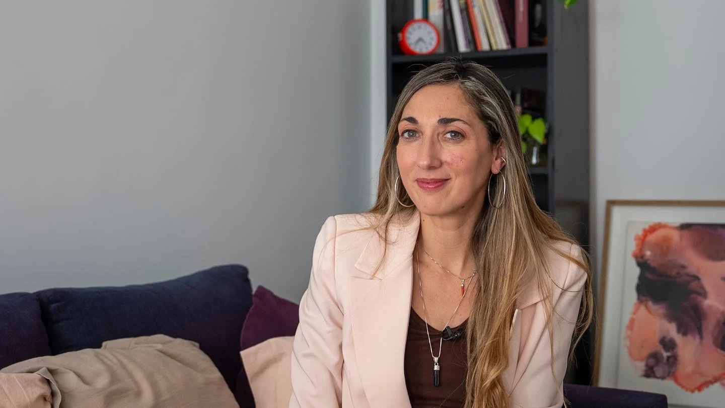 La psicóloga Daniela Gasparini sentada en un sofá, analizando la violencia en relaciones interpersonales