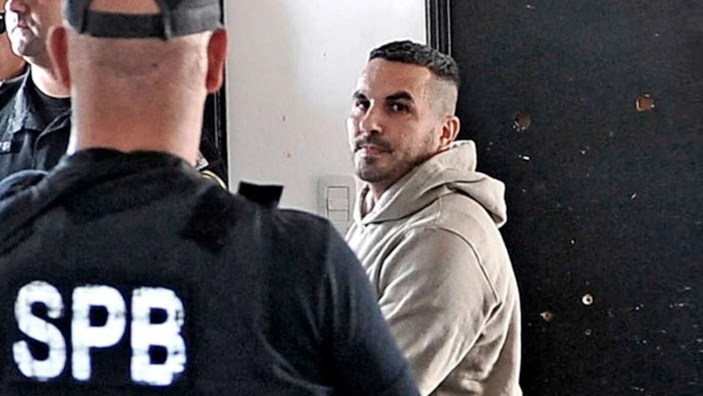 Hombre sentado frente a policías en un ambiente de interrogatorio