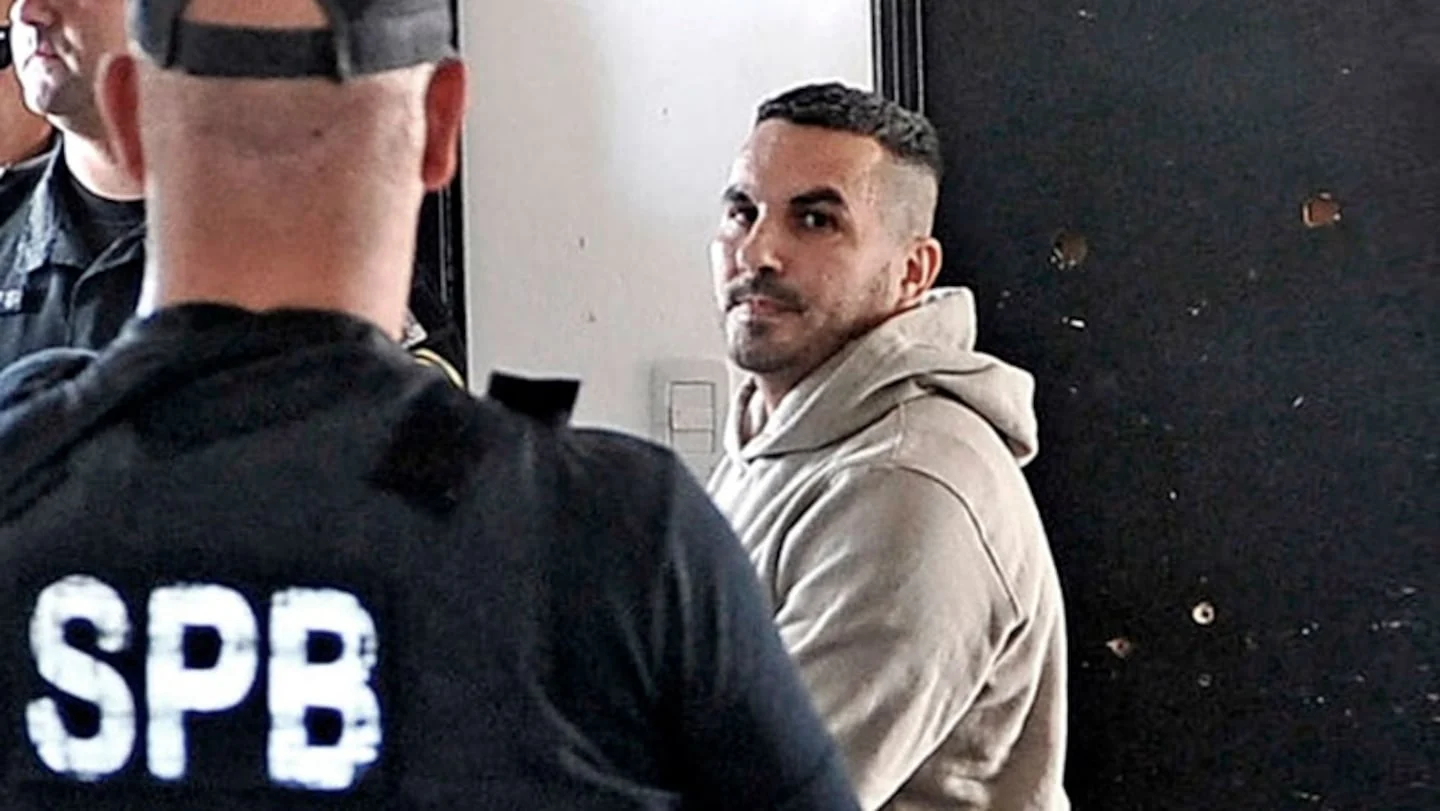 Hombre sentado frente a policías en un ambiente de interrogatorio