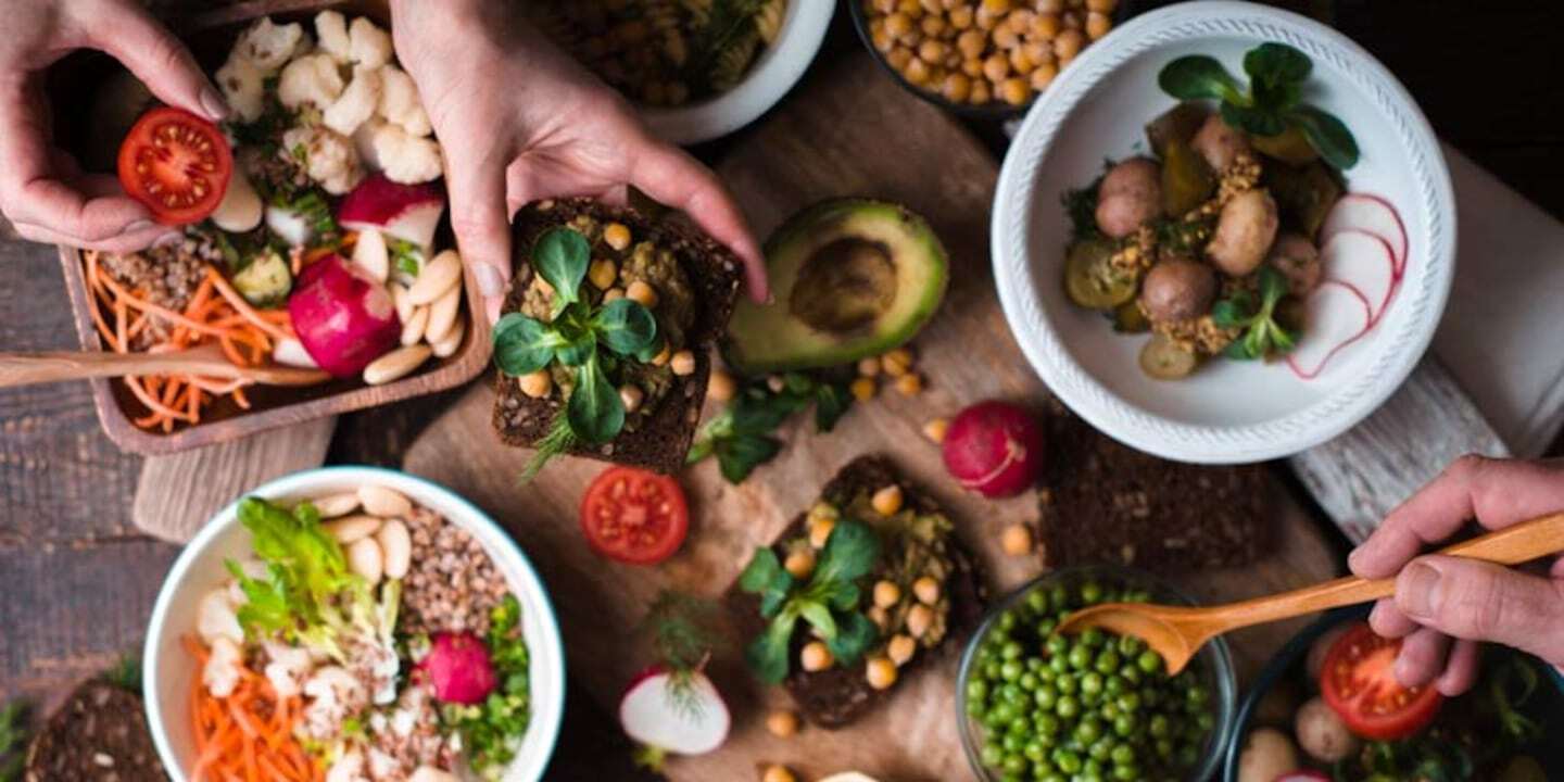 Mesa con variedad de platos saludables y coloridos que incluyen verduras, legumbres y granos