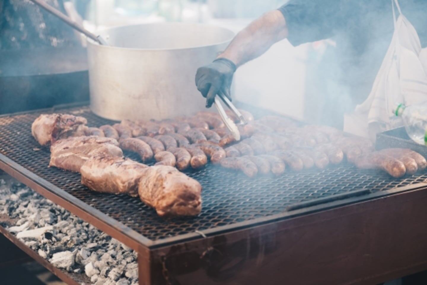 Asador cocinando carne y salchichas a la parrilla