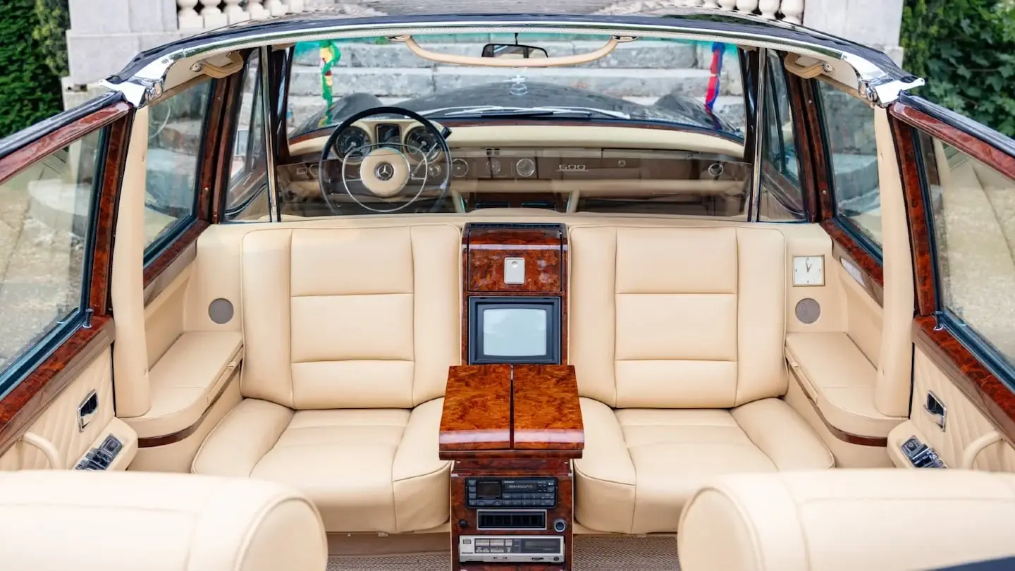 Interior de una limusina Mercedes-Benz 600 Pullman Landaulet con asientos de cuero claro y detalles de madera