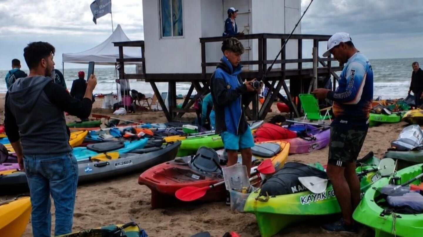 Grupo de jóvenes en la playa de Mar del Plata con kayaks de colores