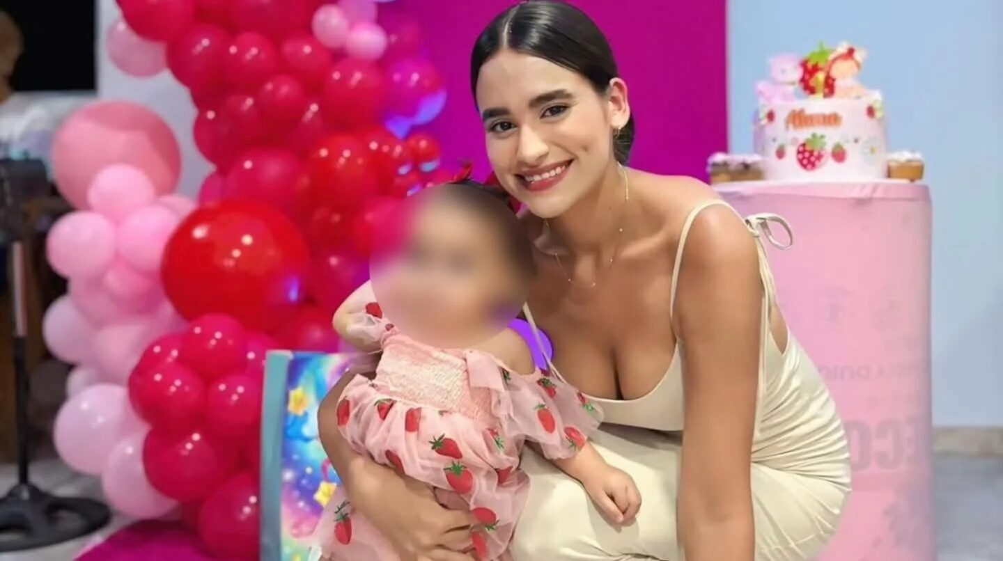 Madre sonriente sostiene a su hija en un ambiente festivo